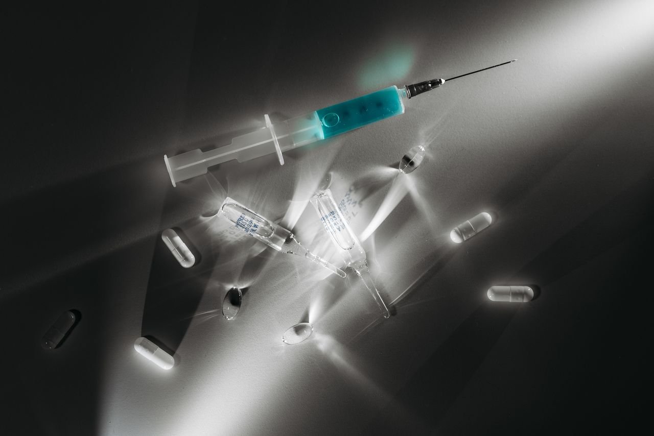 services-03 High contrast image of medical supplies, including a syringe and capsules, in a monochrome setting.